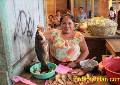 Fish vendor in addition to onlookers behind in market of San Pedro la Laguna